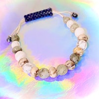 a bracelet with white and gray beads on top of a colorful background
