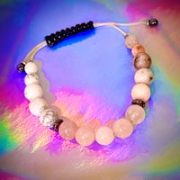 a pink and white beaded bracelet on a colorful background